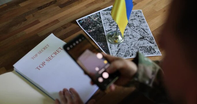 Military spy examines documents about Ukrainian counteroffensive and takes pictures with smartphone. War of Ukraine and Russia