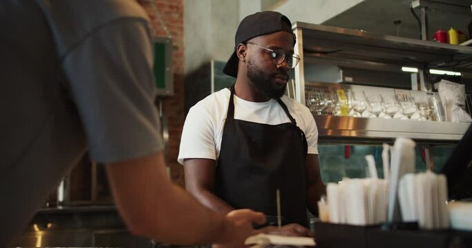 A man takes an order and serves a doner market visitor. Takeaway, keyholder service at fast food establishments