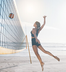 Woman, jump and volleyball on beach by net in serious sports match, game or competition. Body of...