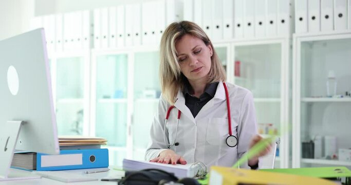 Woman doctor puts documents in folder in clinic. Registration of medical documents