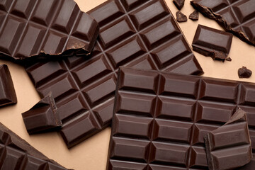 Pieces of delicious dark chocolate bars on beige background, flat lay