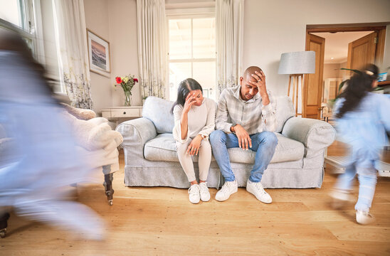 Motion blur, stress and parents with adhd children on a sofa in the living room of their home feeling burnout. Family, kids running or playing with a mom and dad eyes closed in a house for a break