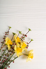 Bouquet of yellow daffodils and beautiful flowers on white wooden table, top view