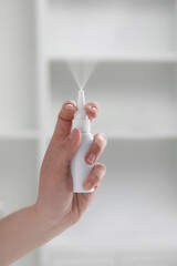 Woman using nasal spray indoors, closeup view