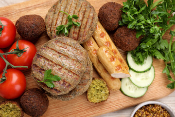 Different tasty vegan meat products and fresh vegetables on wooden table, flat lay