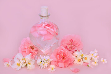 Rose orange blossom and nemesia flower perfume in heart shaped bottle on pink with flowers. Natural floral pure beauty product, gift for Valentines Day, birthday, anniversary or Mothers day.
