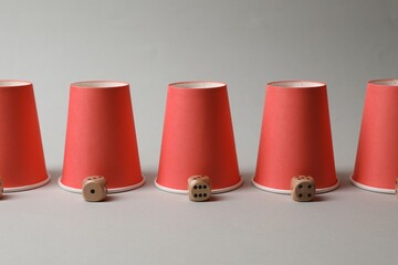 Red cups and dices on light grey background. Thimblerig game