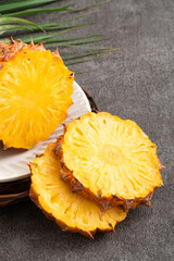 Fresh cut sliced pineapple in a plate over dark gray table background.