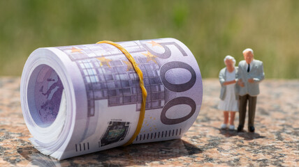 Fototapeta premium A stack of banknotes in denominations of 500 euros and figurines of an elderly couple 