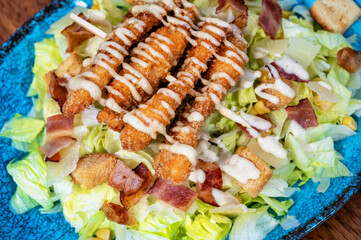 A delightful dish of skewered chicken pieces coated in a crispy batter, elegantly served atop a bed of fresh green salad. 