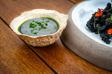 An exquisite example of haute cuisine, this small bowl resembles a stone and contains a delightful green sauce