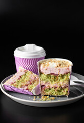 Takeway cake in a glass with pistachios, strawberry mousse and strawberry confit on gray plate