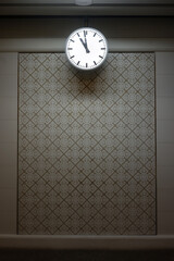 The clock hangs on the white wall.