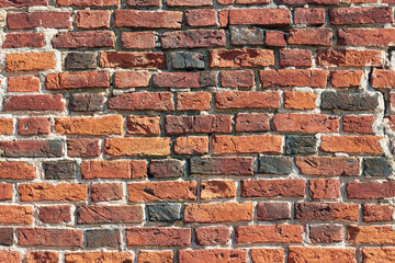 Wall of antique handmade baked bricks with cracks and holes
