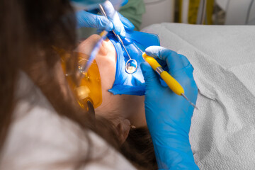 Applying resin based composite filling on tooth. Young woman at dental clinic. Female dentist with...