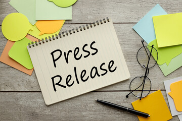 Press Release a lot of stickers are scattered on a wooden background with text on a notepad