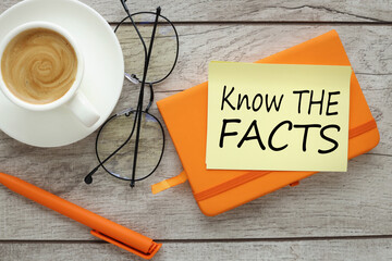 know the facts symbol. text on yellow sticky note and desk with orange notepad