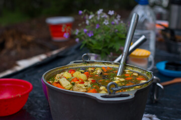 a camp pot hangs over the fire on a tripod. Cooking on a camping trip, hiking