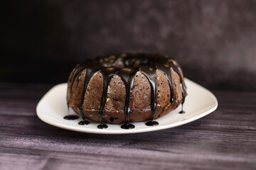chocolate cupcake with icing on a white plate, on a dark background
