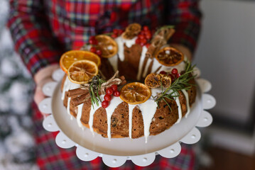 a girl in a plaid dress holds a festive cupcake in her hand, decorated with dry citruses and viburnum