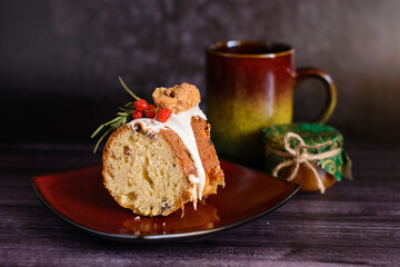 a piece of cake with candied fruits on a ceramic plate, next to a cup, on a dark background