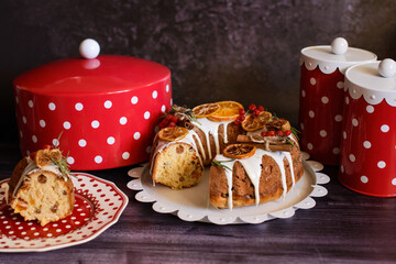 cut cupcake with candied fruits on a plate, next to red containers with white polka dots, on a dark...