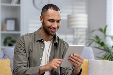 Close-up photo. Young hispanic man using tablet at home. dials, chats, talks via video call