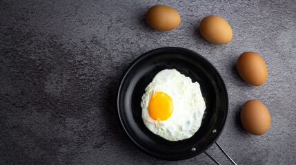 Top view of Breakfast menu fried eggs in an iron pan and raw chicken eggs.