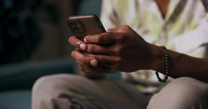 African man sits on a couch, chatting on his cellphone. He could be connecting with his sister who lives abroad, sharing stories and supporting each other despite the distance.