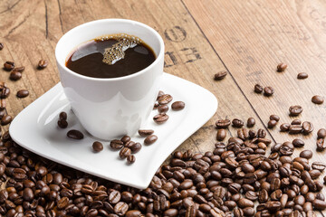 a white cup of coffee and coffee beans on a wooden table