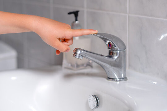 The child turn off the water tap after hygienic procedures. The concept save water and protect the environment. 