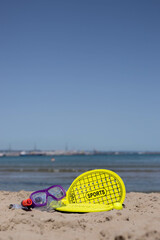 Beach tennis racket , ball, and swimming mask on tne beach