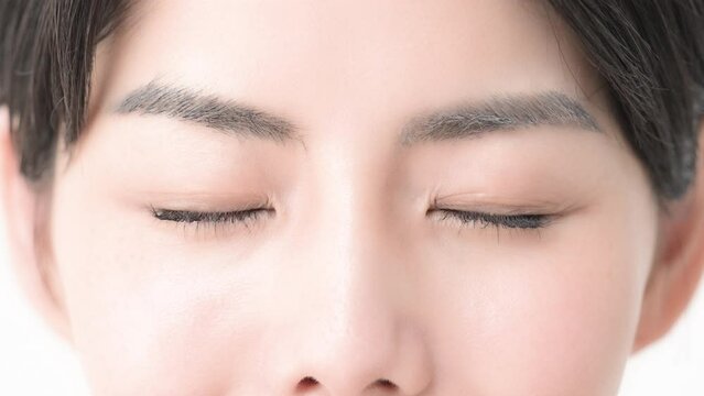 まつ毛が美しい目元のクローズアップ のスロー動画　笑顔で瞬きして目を閉じるカメラ目線