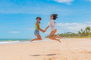 Fototapeta na wymiar Mãe e filha pulando na areia da praia