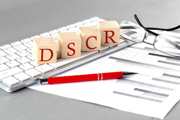 DSCR written on a wooden cube on the keyboard with chart on grey background