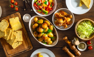 Home dinner table with set of various food from baked new potatoes with fried chicken legs,...