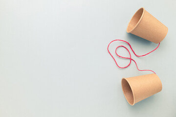 Paper cups phone with red string on empty clear background, two-way communication, talk to each...