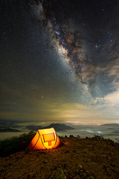 Yellow tent on top of mountain in night sky stars with Milky Way