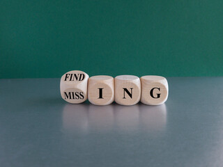 Finding or missing symbol. Turned wooden cubes and changes the word missing to finding. Beautiful green background. Business, finding or missing concept. Copy space.