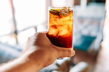 man hand hold glass coktail Cuba Libre with brown rum, cola and lemon