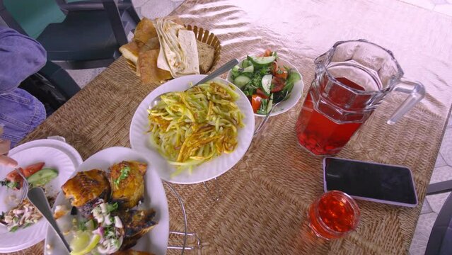 Happy woman eating fried fish in Restaurant and chatting, speaking on camera. On table is red dogwood compote, potatoes, salad. Dinner at diner and cheap table. Restaurant Cheap.