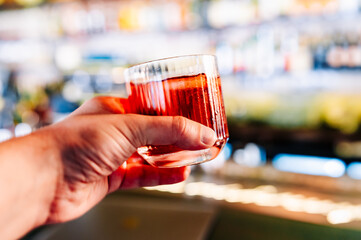 man hand hold glass red coktail in bar