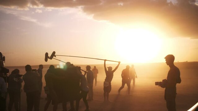 A film crew filming a film in a sandstorm. Beautiful sunset landscape.  film movie production in extreme conditions in the desert.