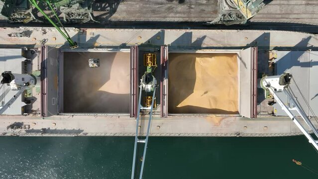 Loading dry cargo ship of wheat by cranes in port. Aerial view loading into holds of sea cargo vessel