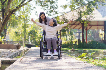 Asian senior woman in wheelchair with happy daughter. Family relationship retired woman sitting on wheelchair in the park age care at retirement home. © Charlie's