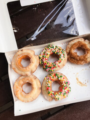 Donuts, box of assorted, store-bought old-fashioned sour cream doughnuts with sugar glaze, sprinkles and cinnamon sugar topping outside for picnic - 620585756