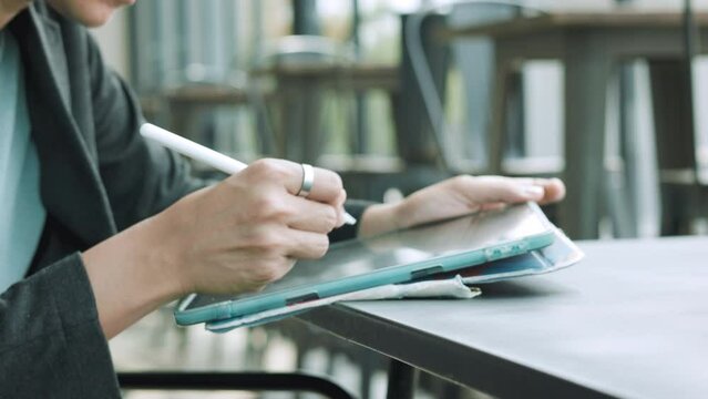Hands with stylus tablet of Asian woman embraces the modern lifestyle. Witness the authentic connection she creates through the social network, leveraging wireless technology to excel as an executive.
