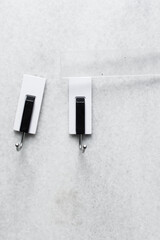 Sticky adhesive hooks on a white wall, white and black adhesive wall hooks on a white wall