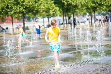 happy boy playing in dry fountain in summer