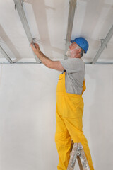 Senior adult worker placing aluminum profile for gypsum ceiling and insulation